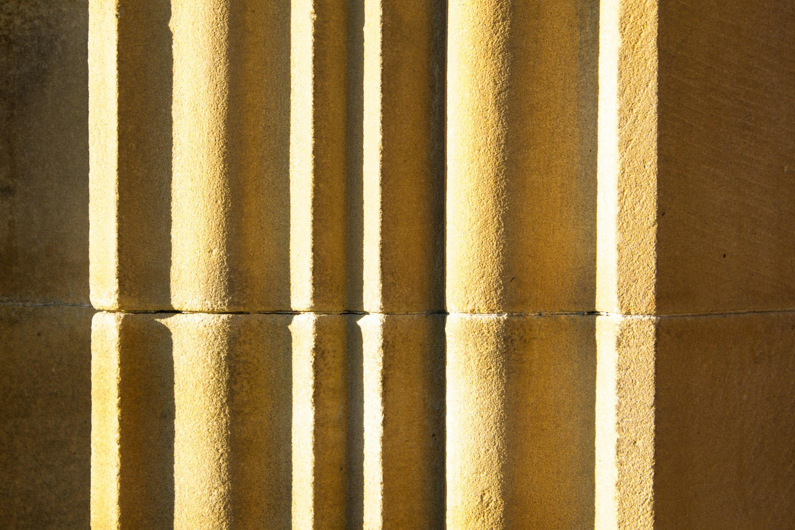 Mur de pierre calcaire cannelé sous une lumière chaude